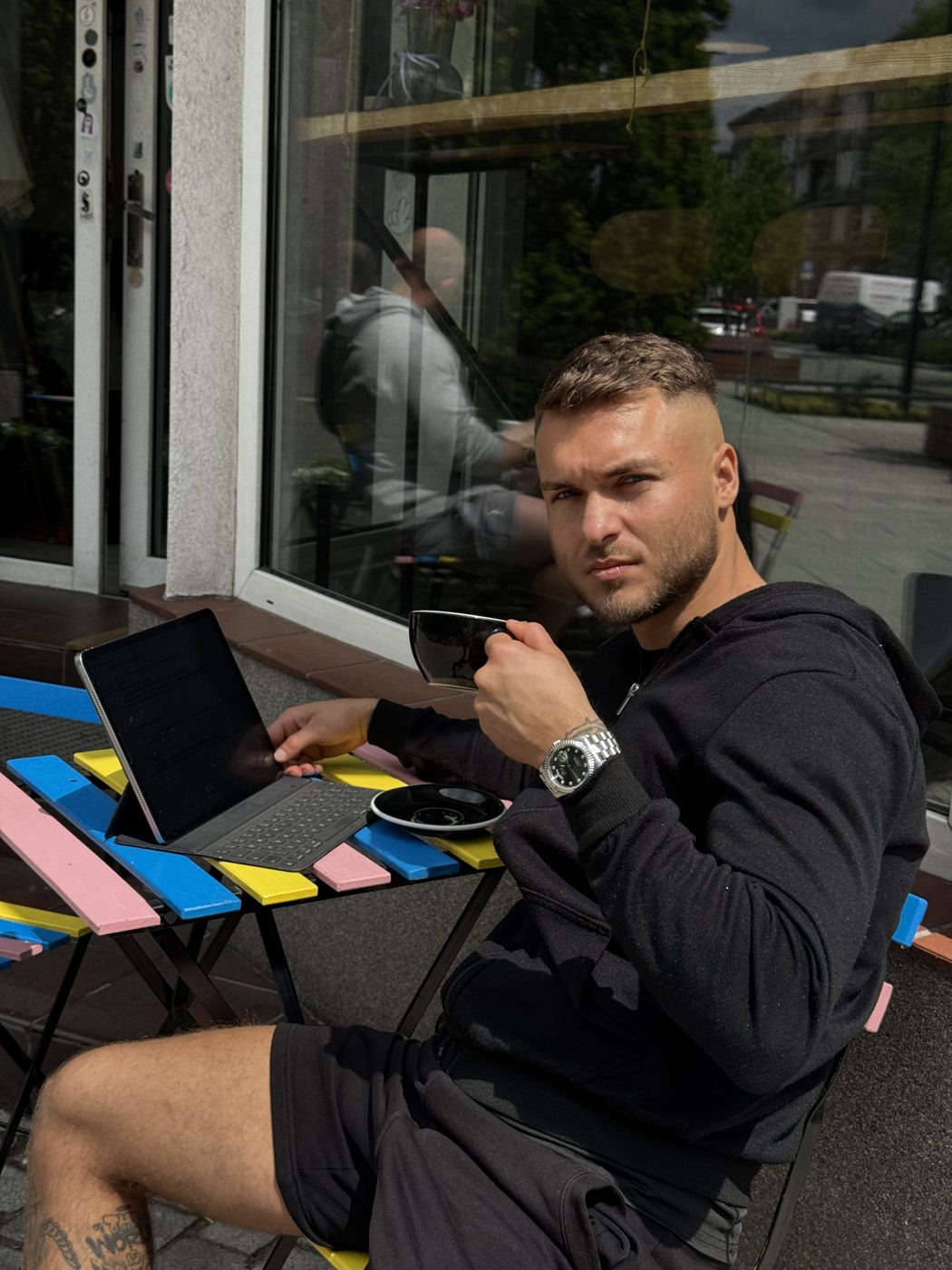 Michał przy stoliku z kawą i tabletem, czyta podsumowanie tygodnia